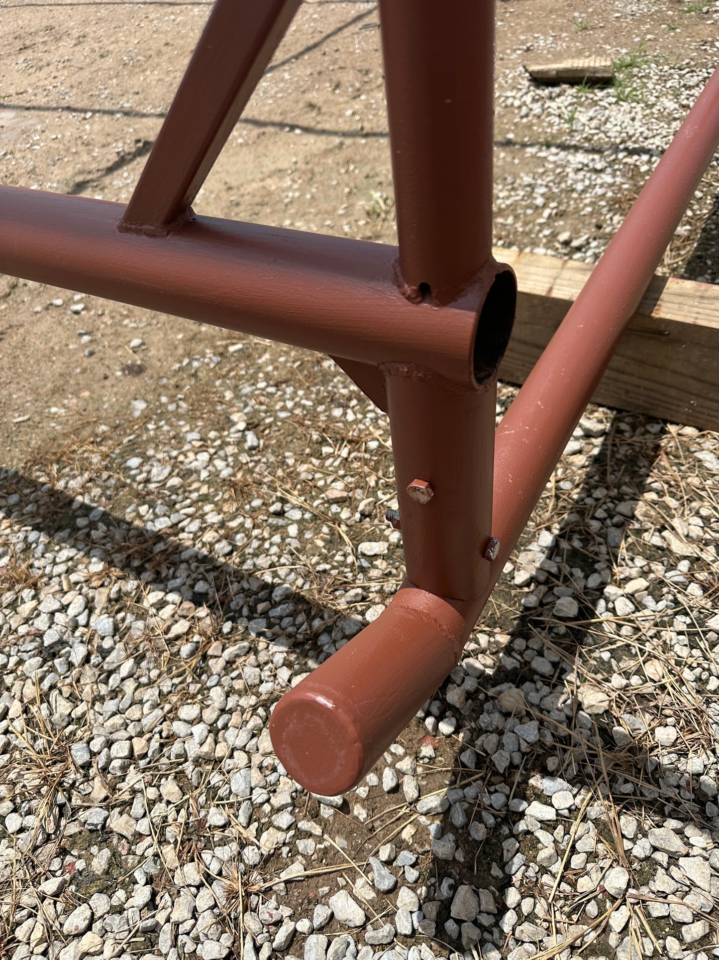 Red-oxide metal shelter frame on a gravel surface