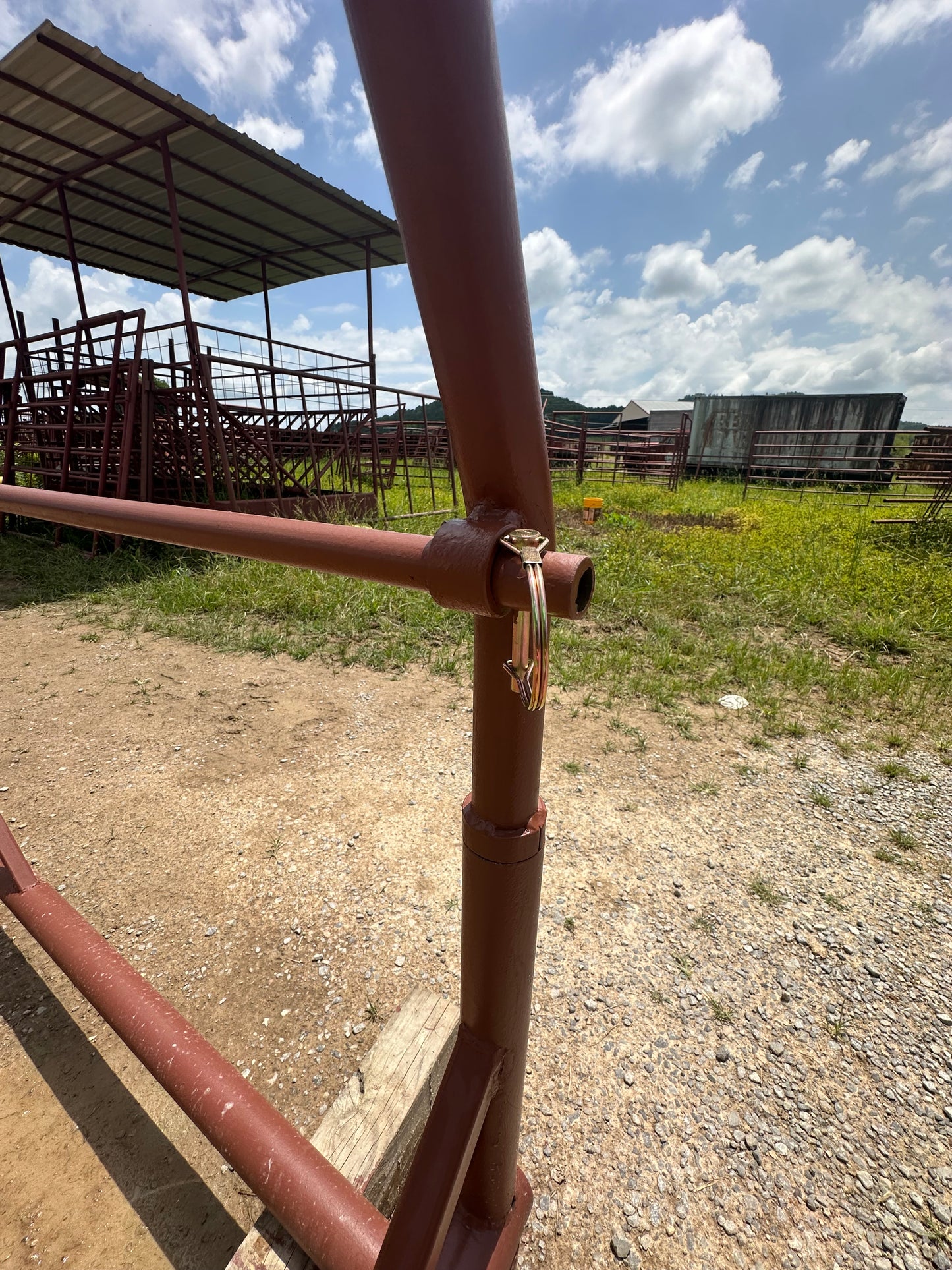 Red-oxide metal pipes on a gravel ground with a blue sky and clouds in the background