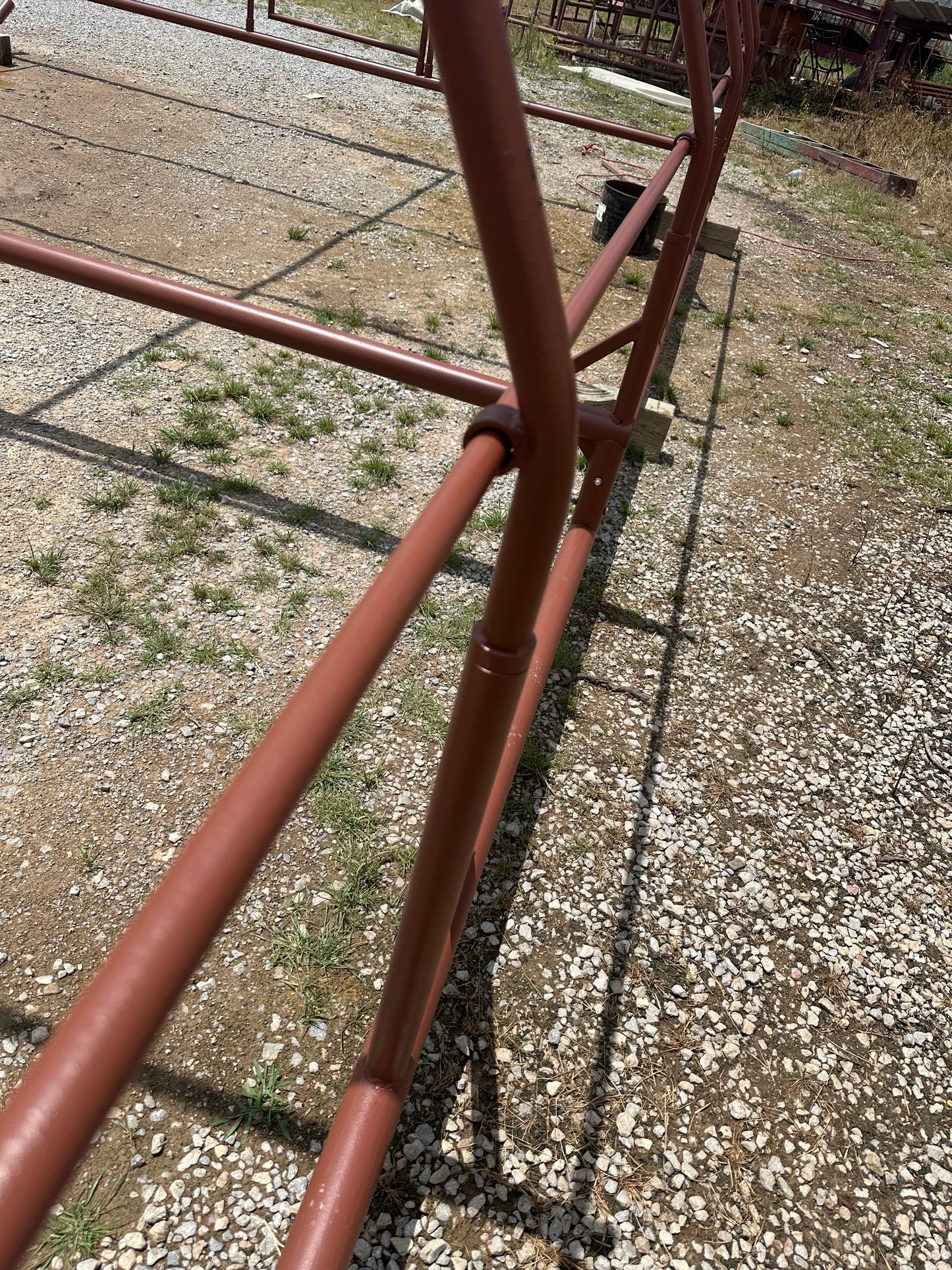 Red-oxide-colored steel chicken shelter structure on a gravel surface