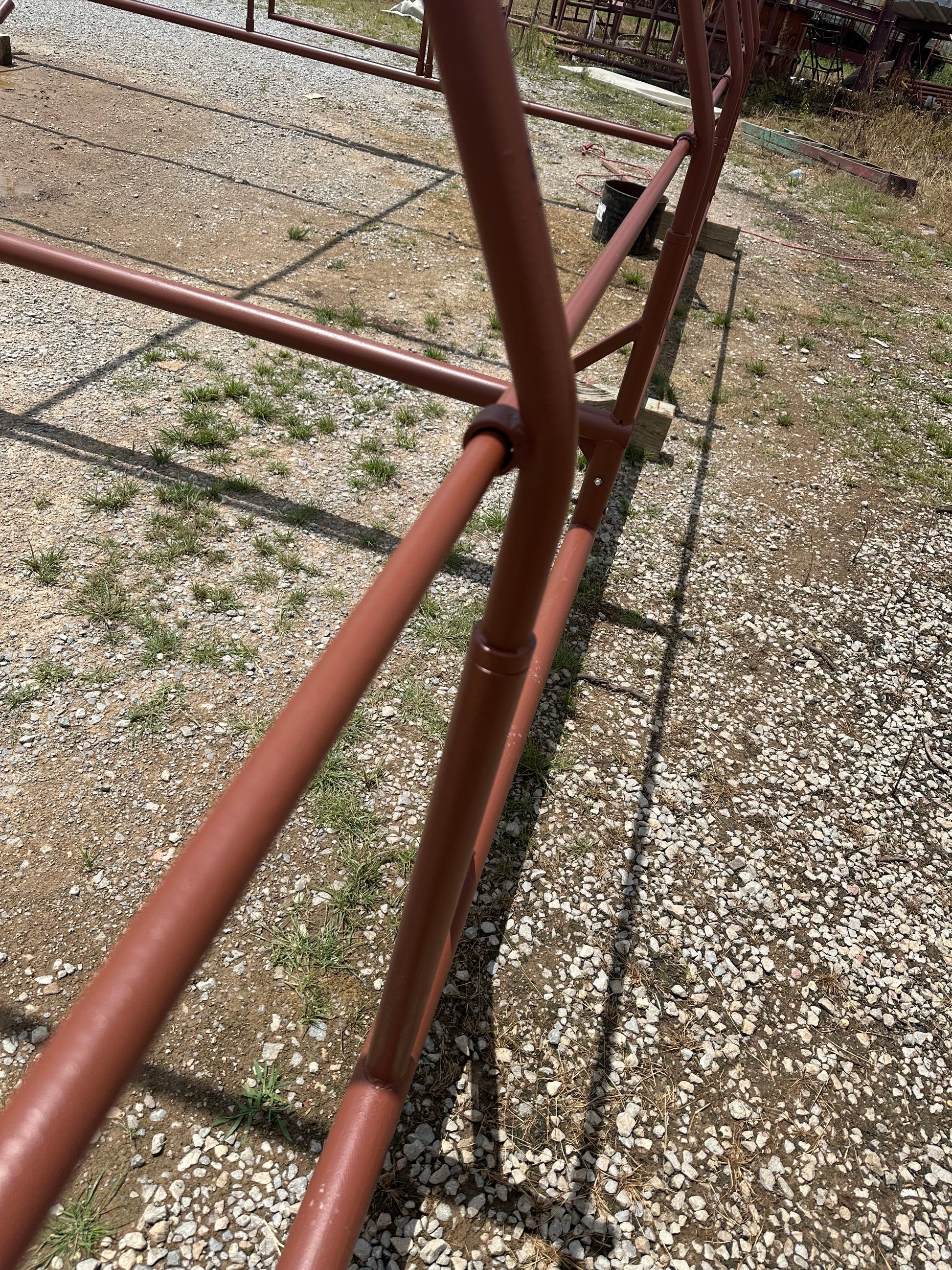 Red-oxide-colored steel chicken shelter structure on a gravel surface